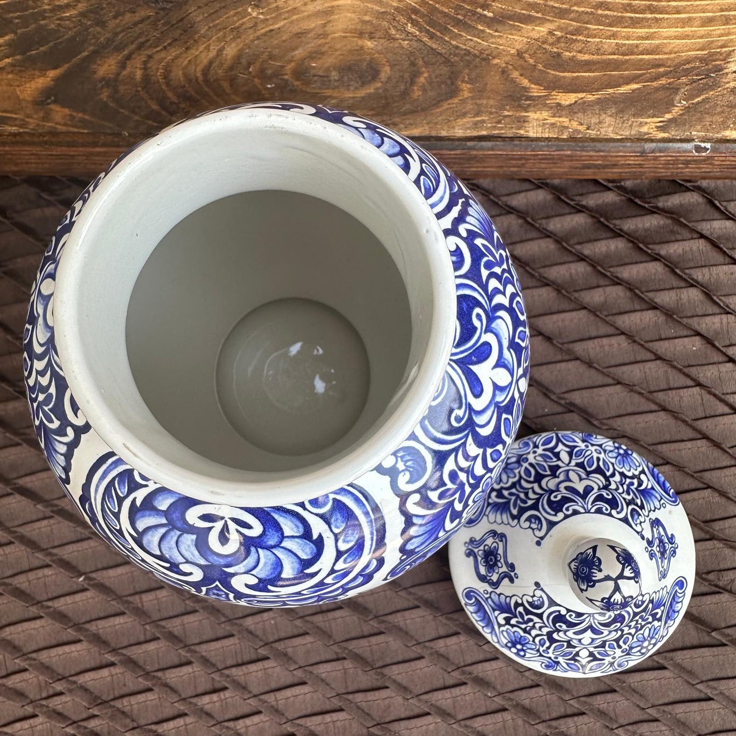 Blue and white ceramic jar with lid on a woven surface