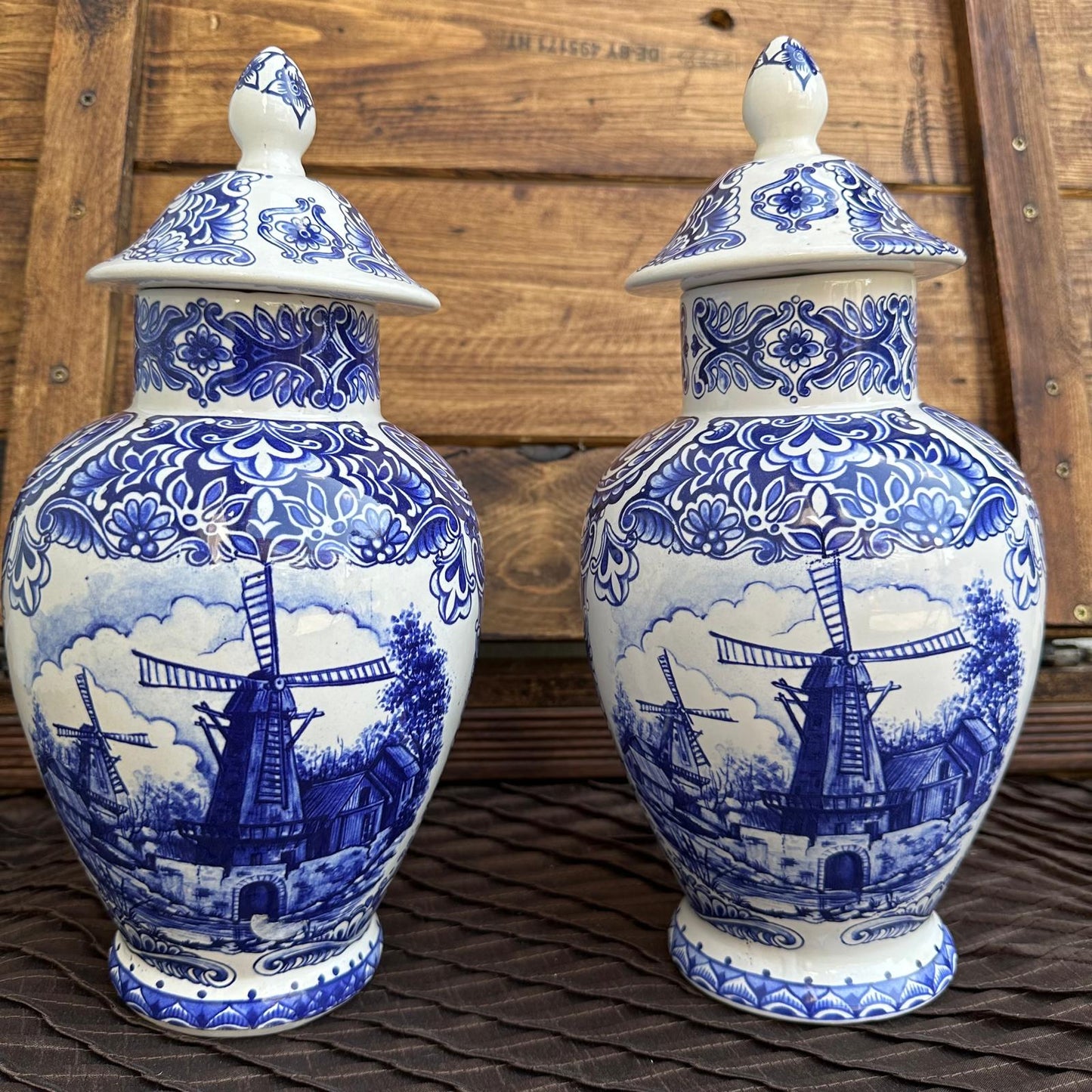 Two blue and white ceramic vases with windmill designs on a wooden surface.