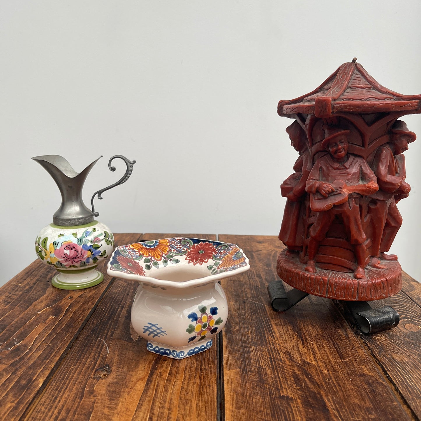 Decorative ceramic pitcher, soap dish, and wooden sculpture on a wooden surface with a white background