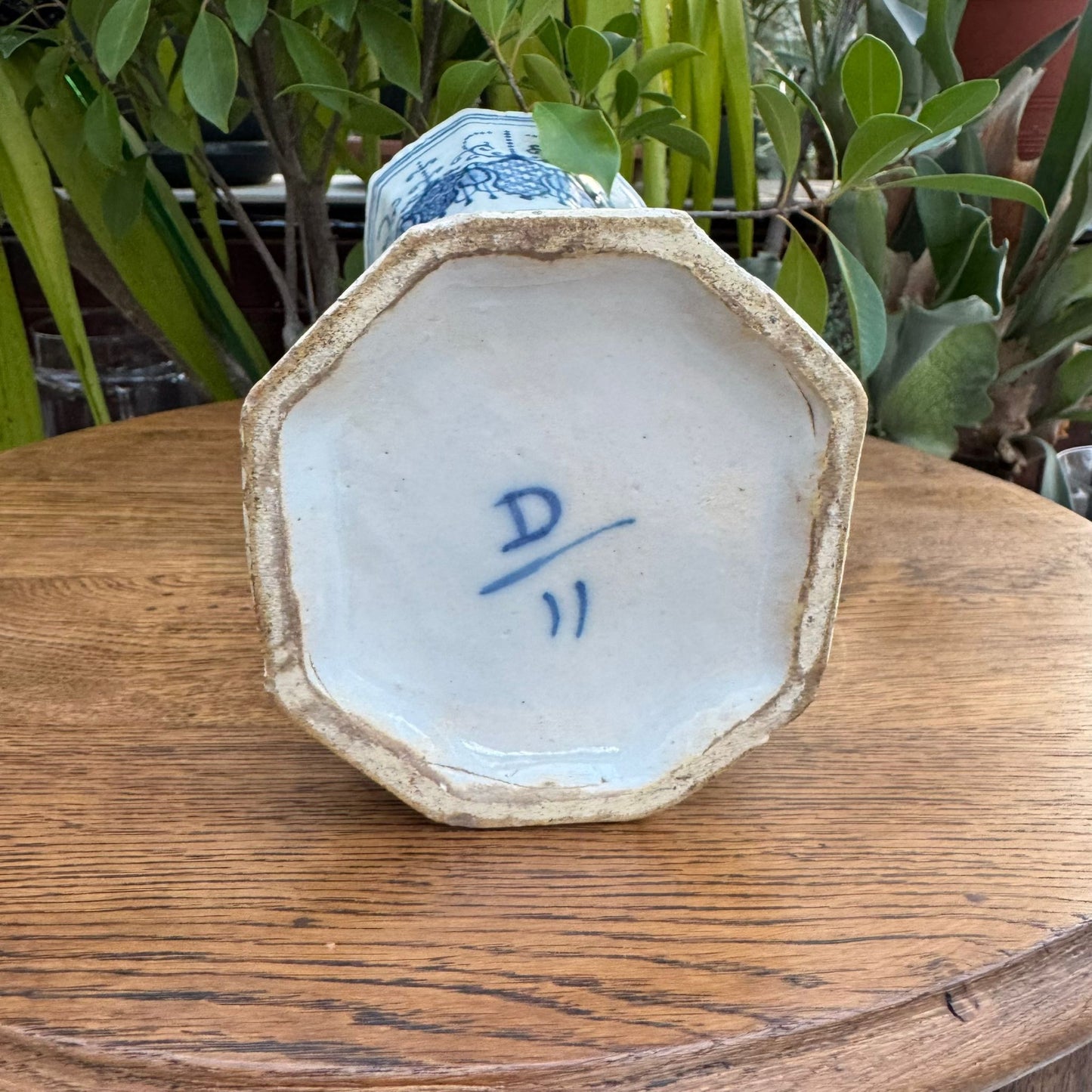 Ceramic bowl with a signature on a wooden surface with plants in the background