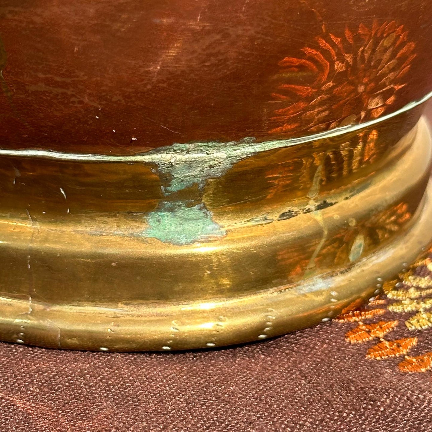 Close-up of a brass object with a textured surface on a fabric background