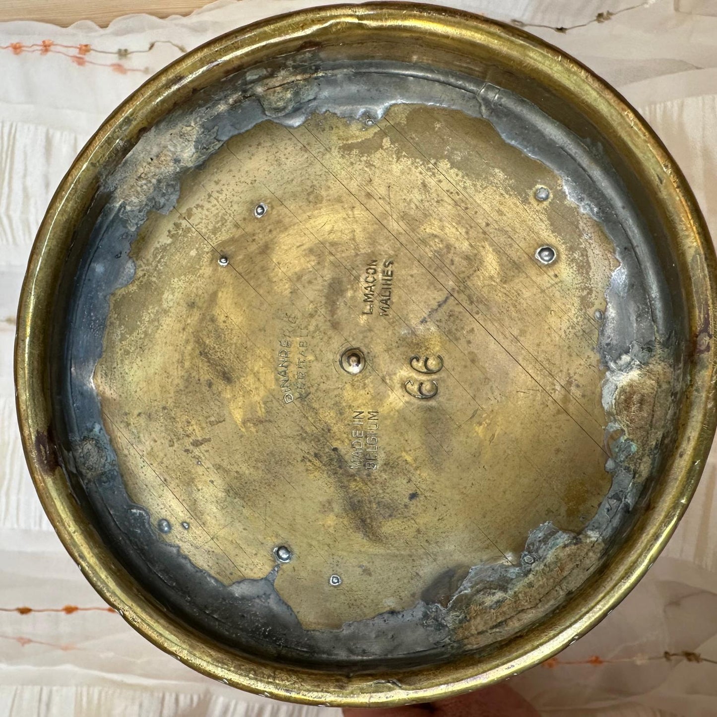 Worn brass lid with visible signs of aging on a textured surface