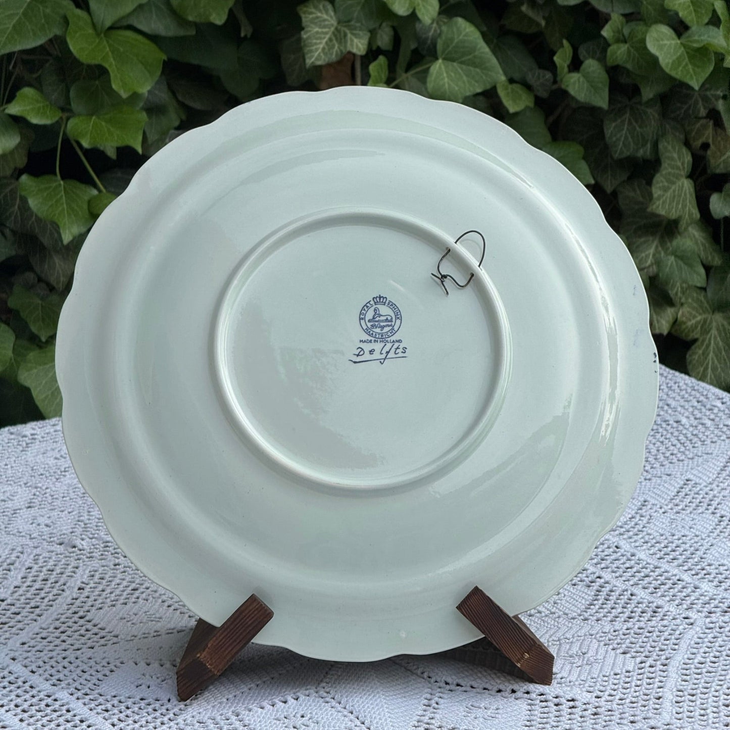 Light green ceramic plate with a visible brand logo on a white lace tablecloth with a green leafy background.