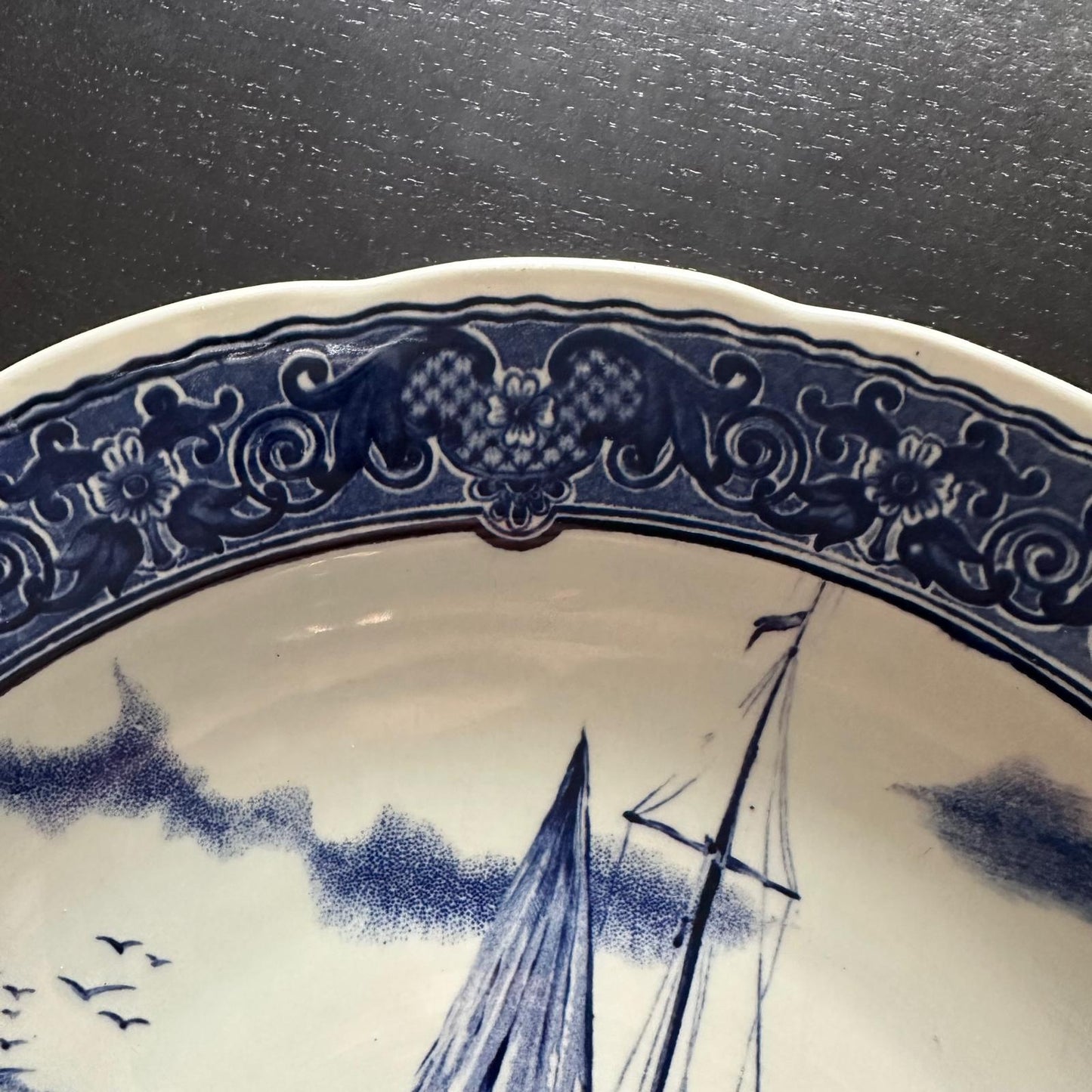 Ceramic plate with blue decorative edge and sailboat design on a white background