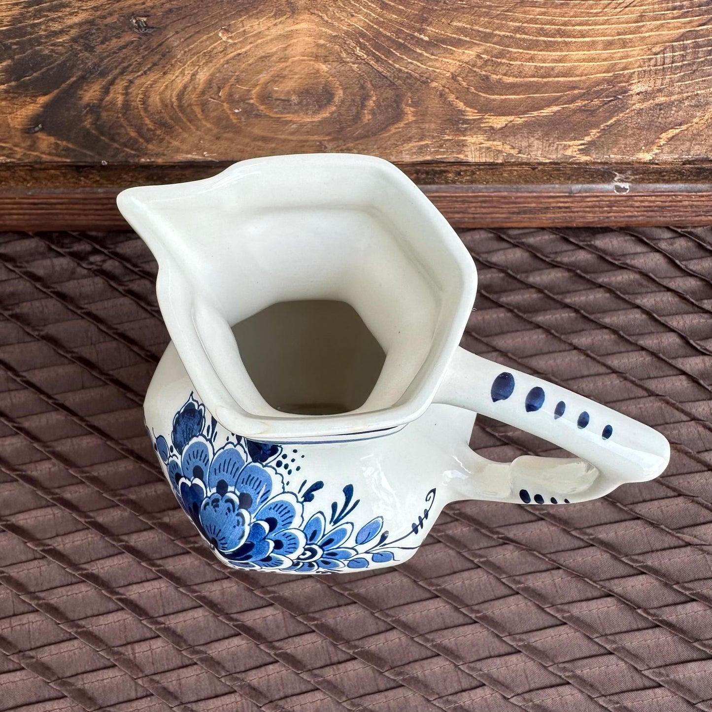 Ceramic pitcher with blue floral design on a woven surface