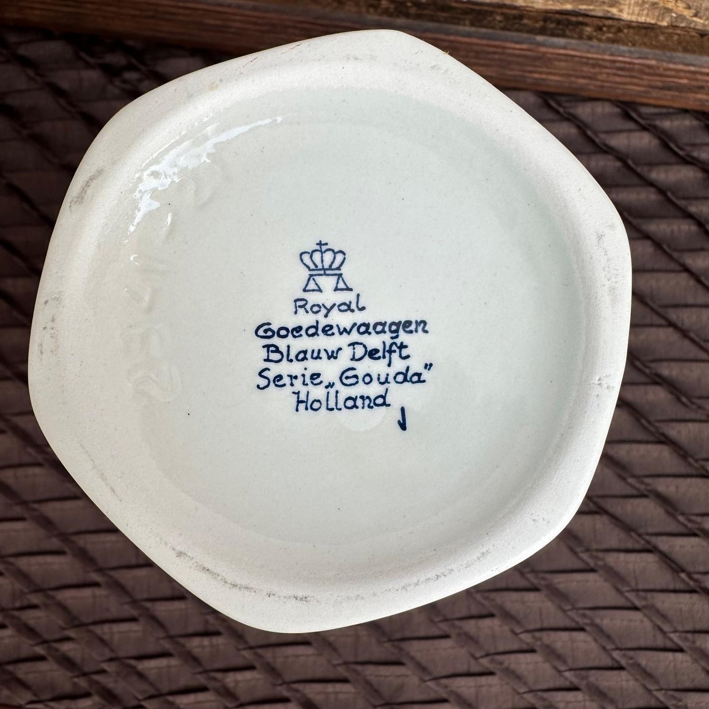 Ceramic plate with 'Royal Delft' branding on a woven surface