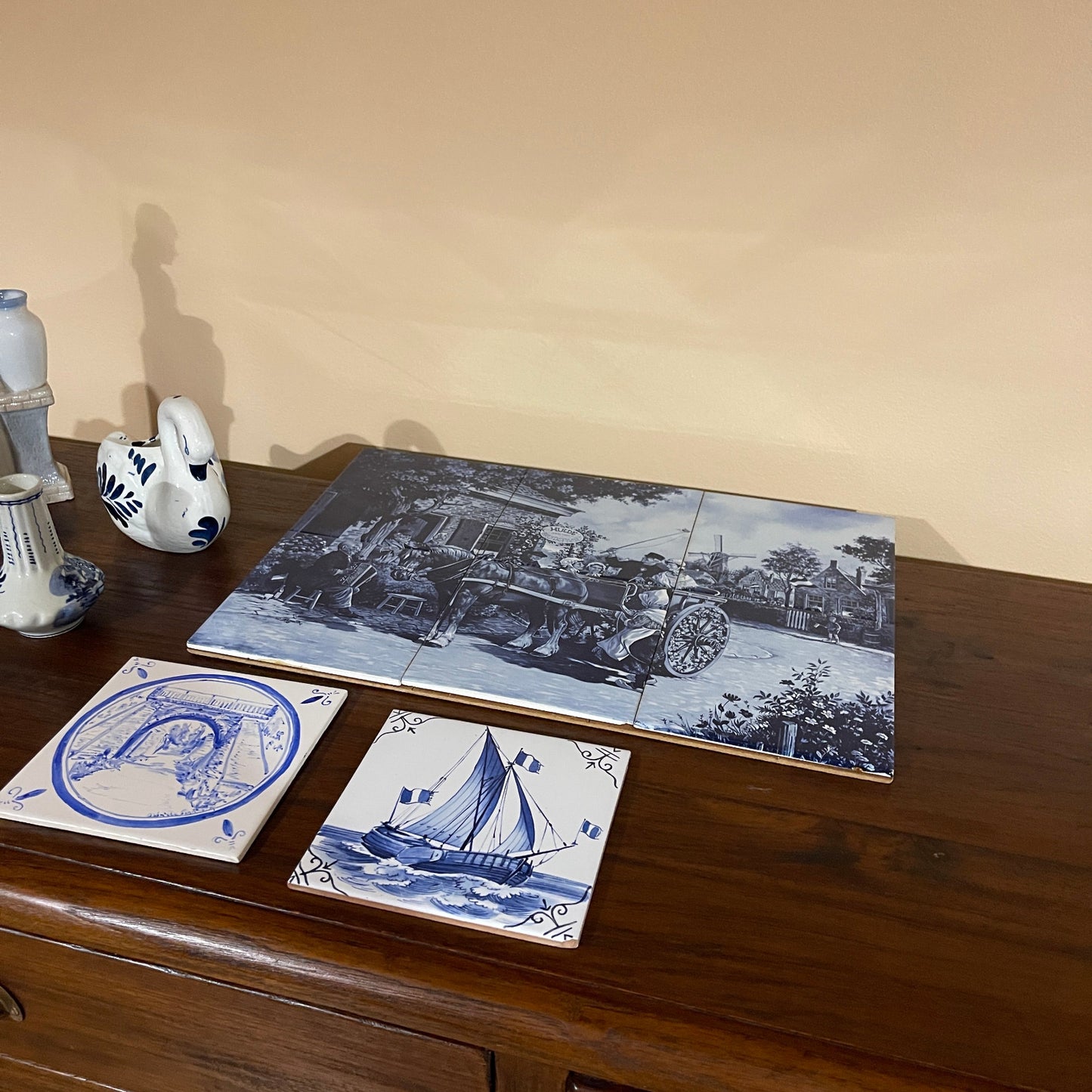 Set of blue and white ceramic tiles with scenic designs on a wooden surface.