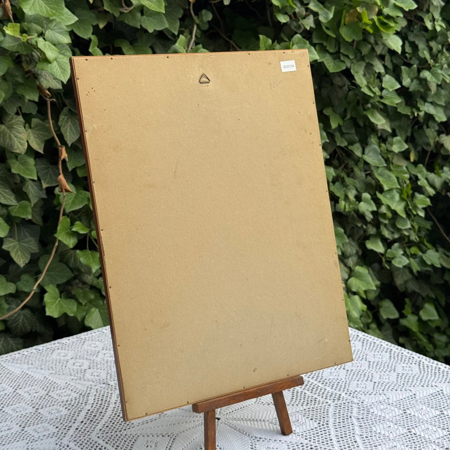 Blank cardboard sign on a stand with a green leafy background