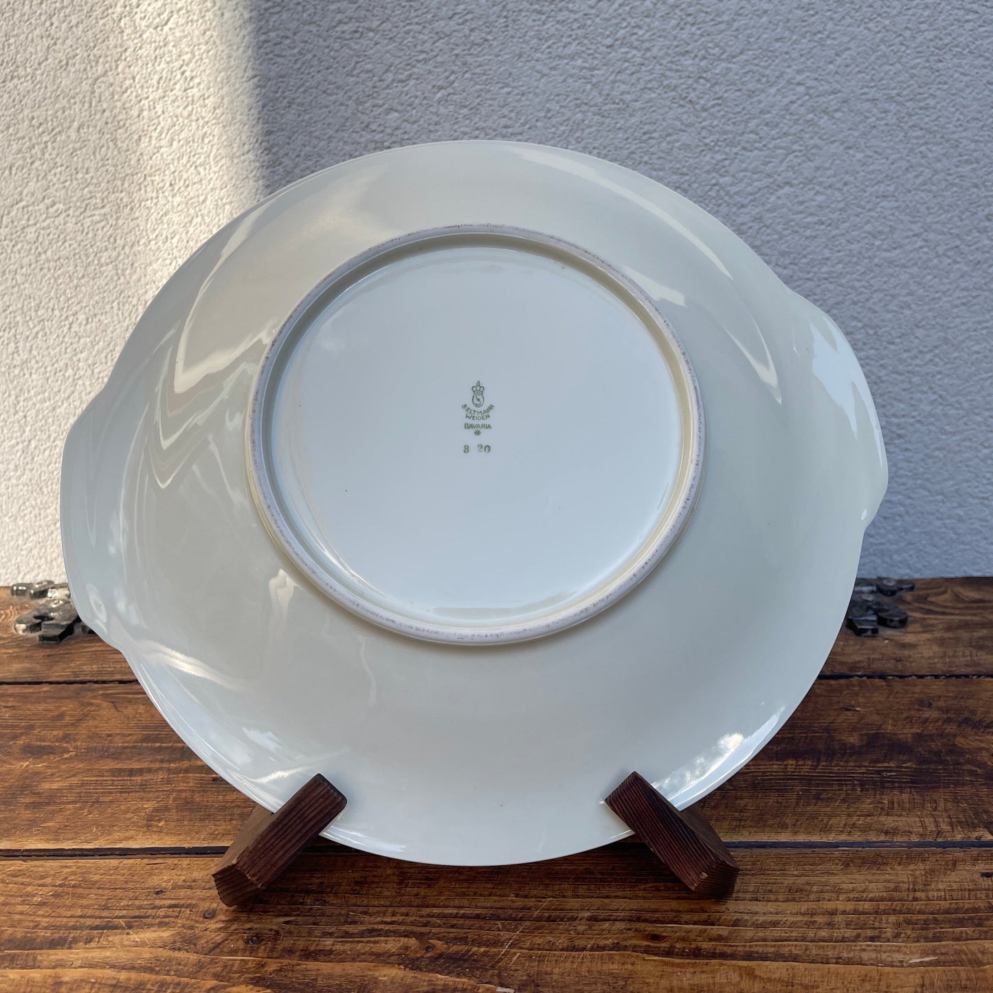 White ceramic plate on a wooden stand against a neutral wall.