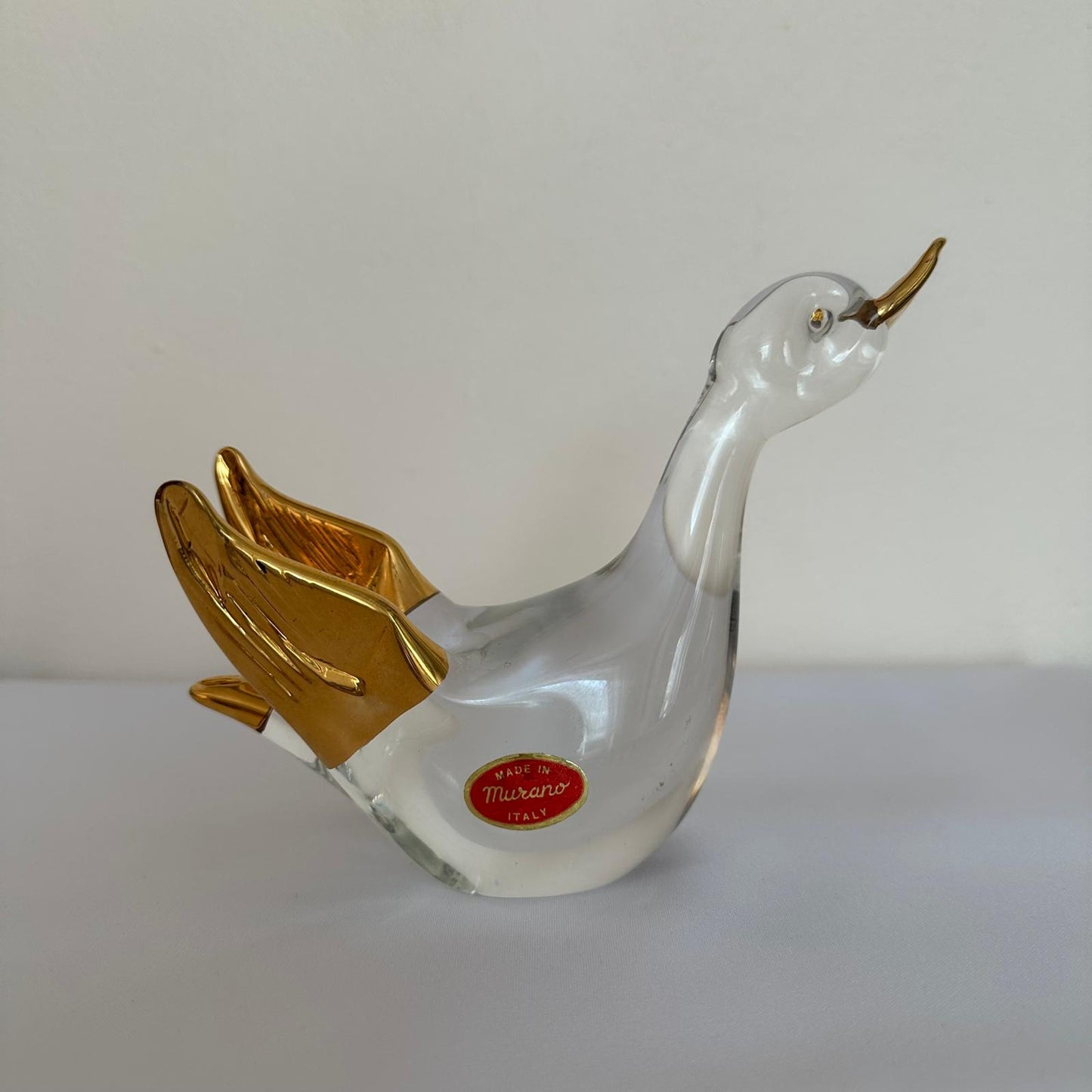 Glass duck figurine with gold accents on a white background