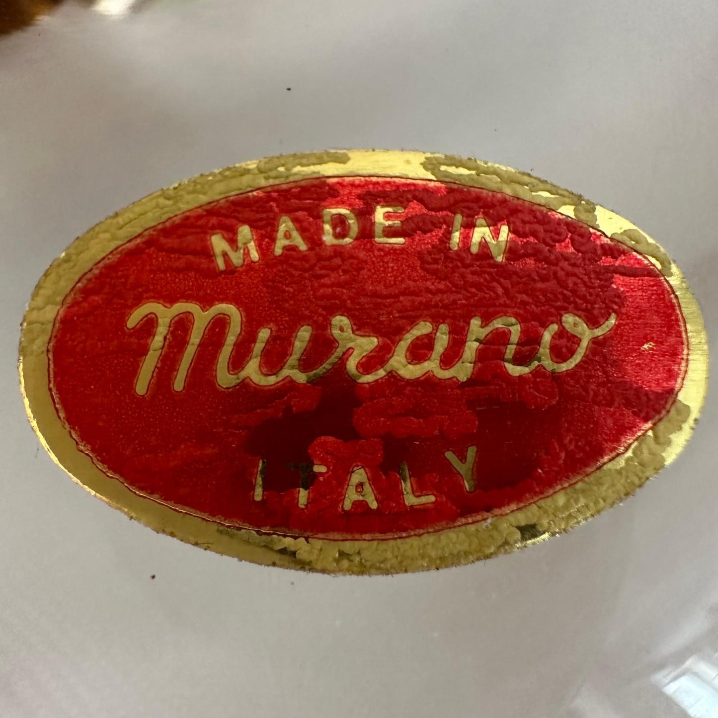 Red and gold 'Made in Murano Italy' label on a white background