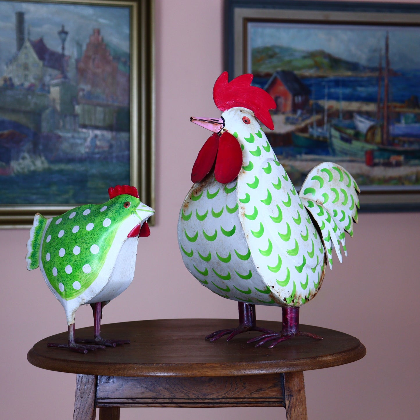 A set of vintage metal garden figurines depicting a hen and chicken, featuring multicolored patterns and signs of rust.