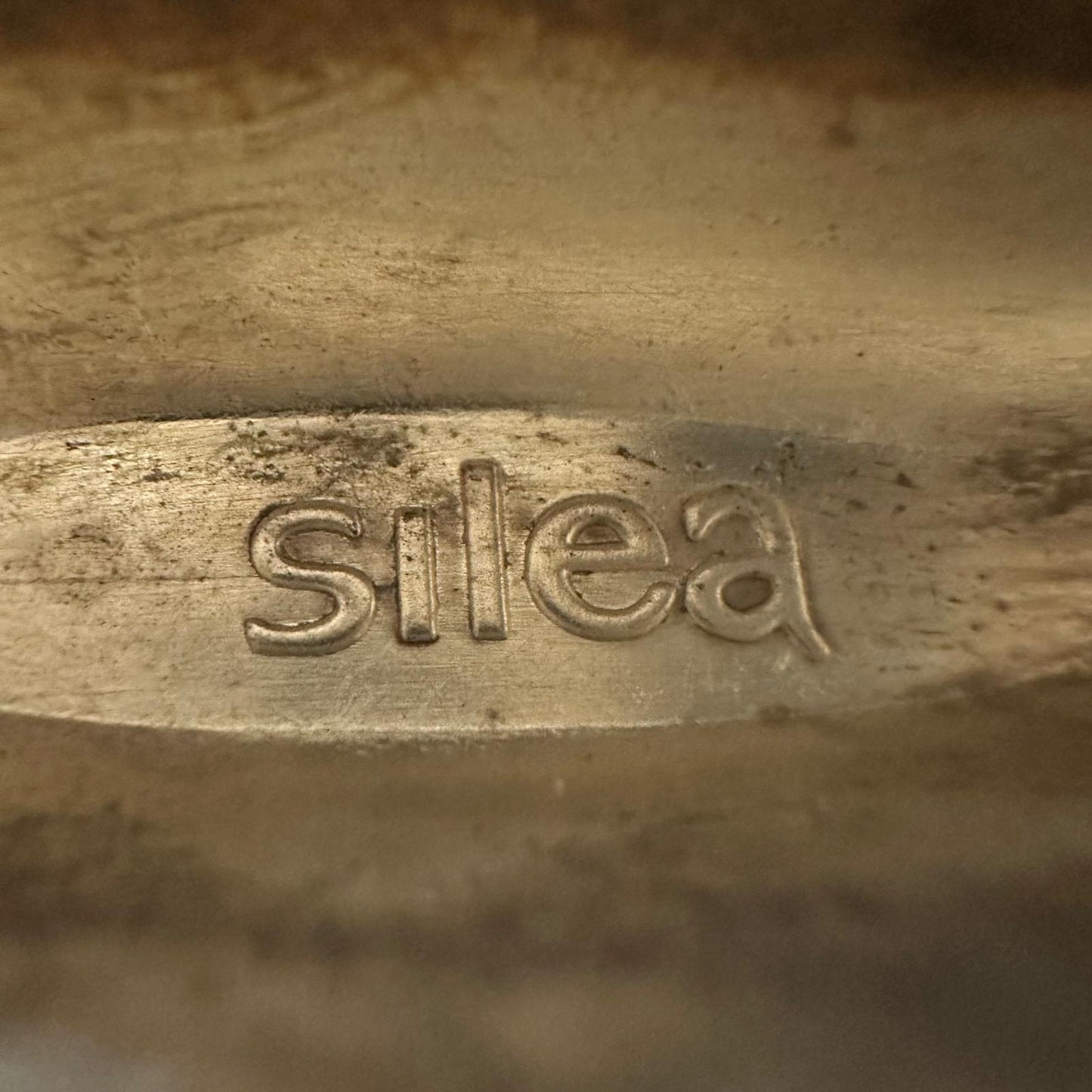Close-up of a metallic object with 'silea' engraved on it.