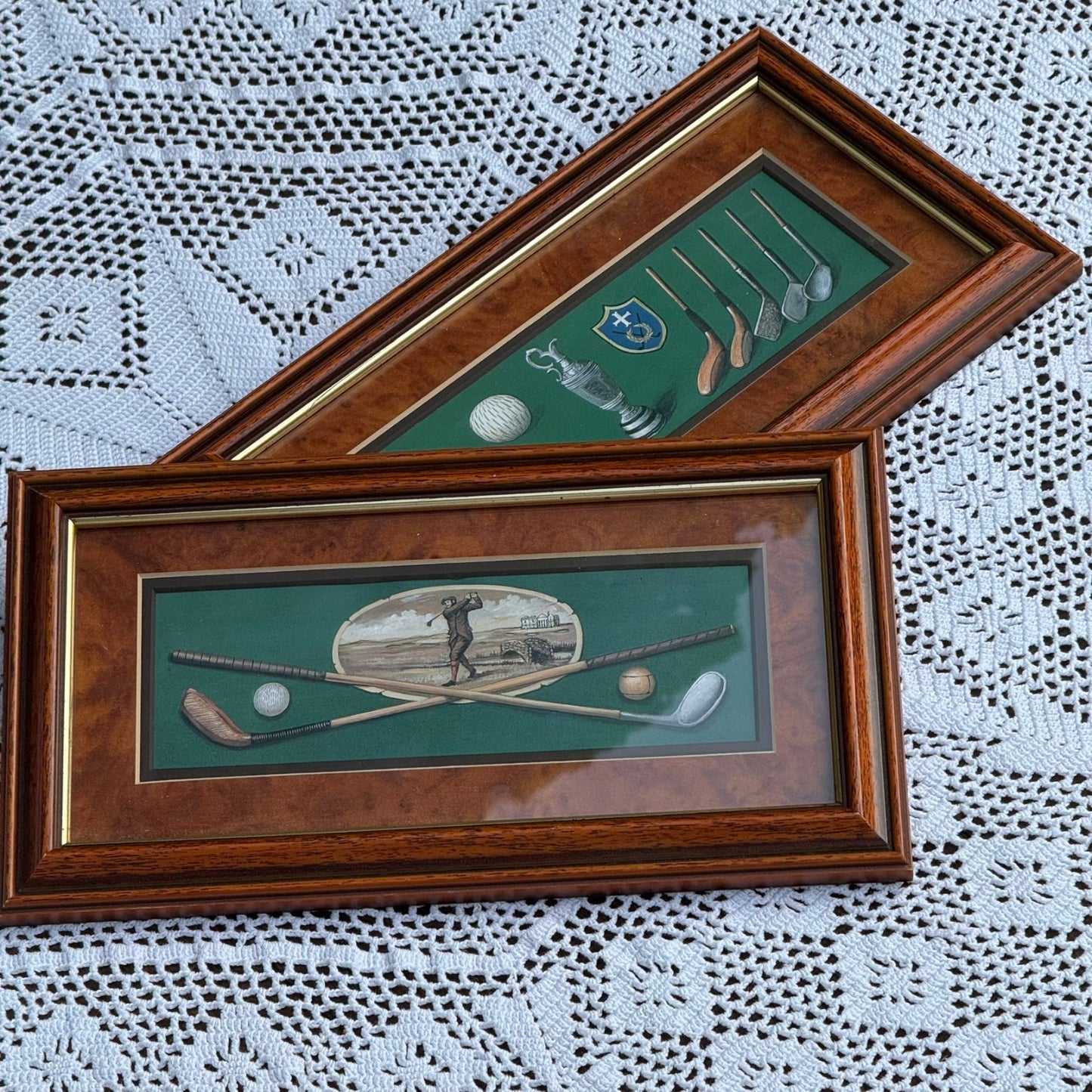 Two framed golf-themed pictures on a lace tablecloth