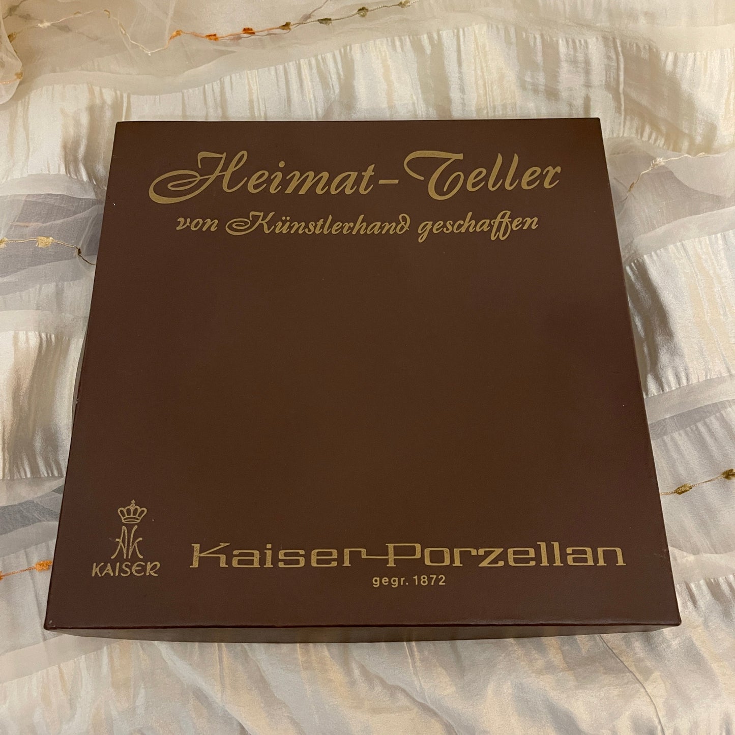Brown box with gold text and Kaiser Porzellan logo on a textured white background