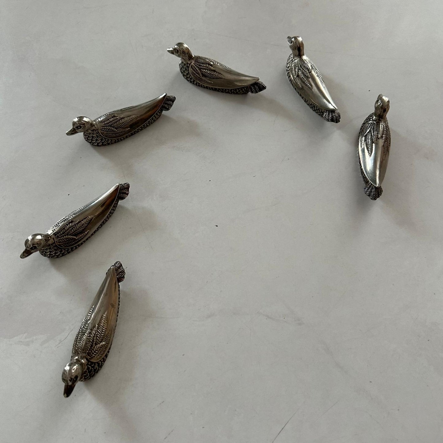 Silver bird-shaped objects on a white surface