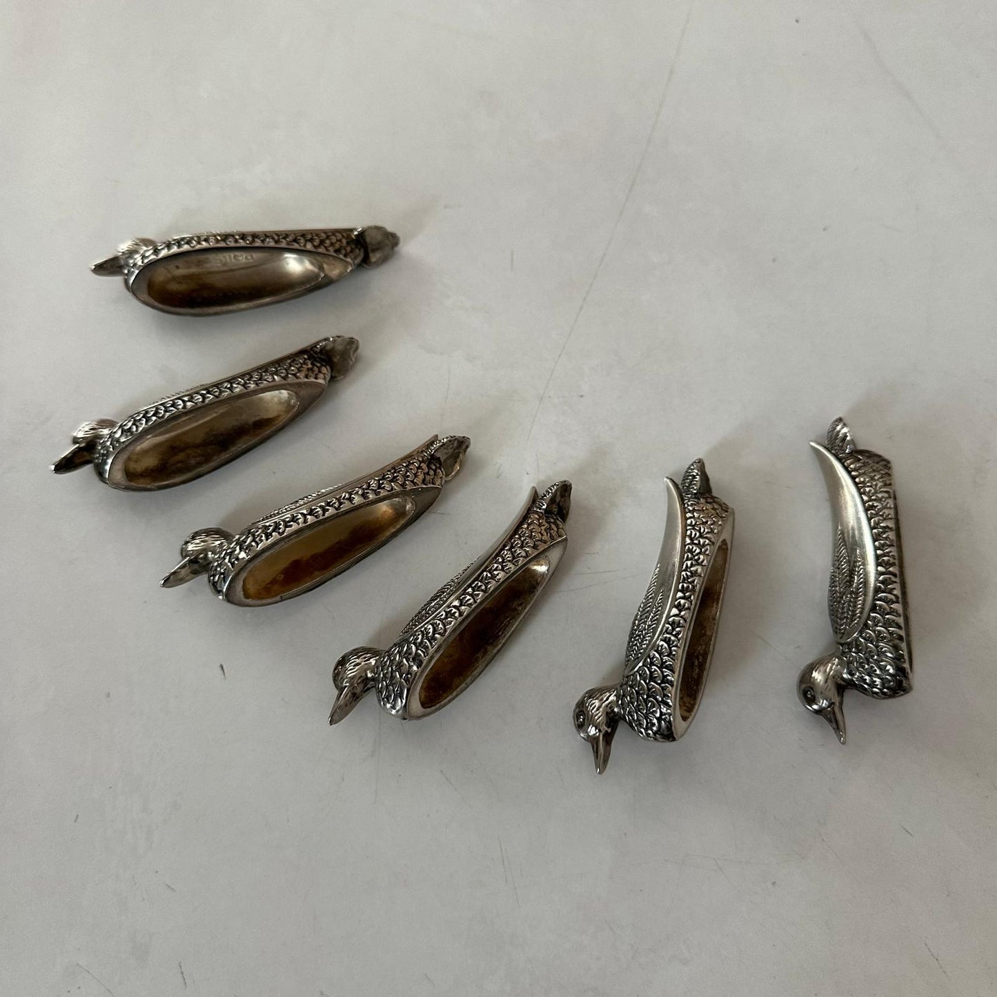 Set of silver bird-shaped decorative items on a white surface