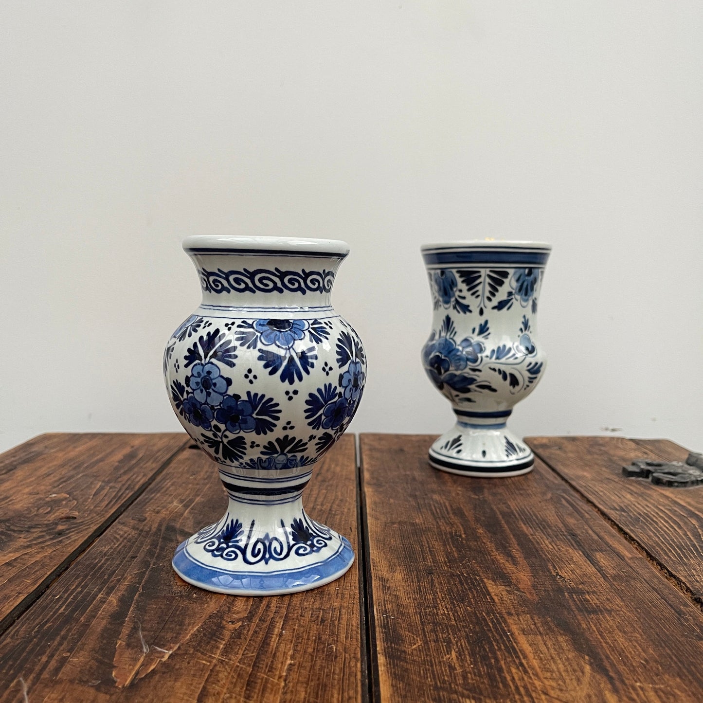 Two blue and white ceramic vases on a wooden surface with a plain background
