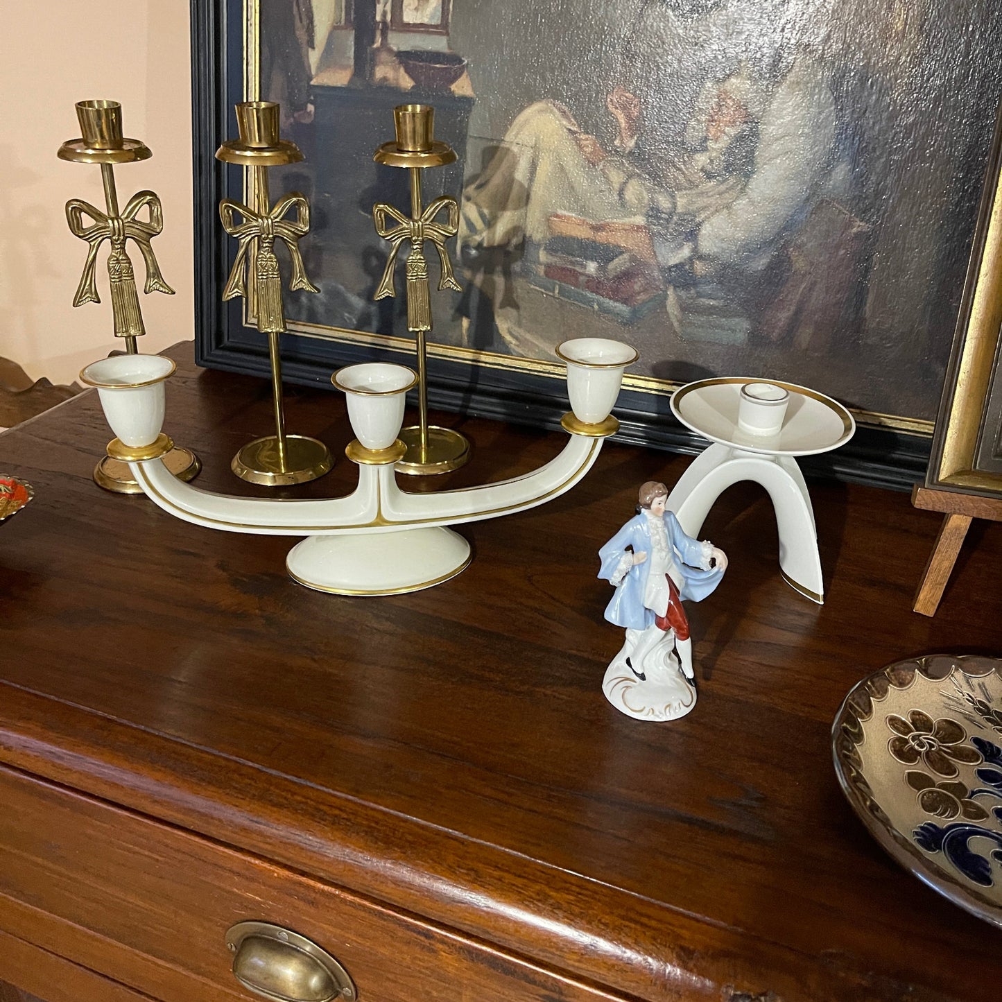 Decorative candle holder on a wooden surface with a painting in the background