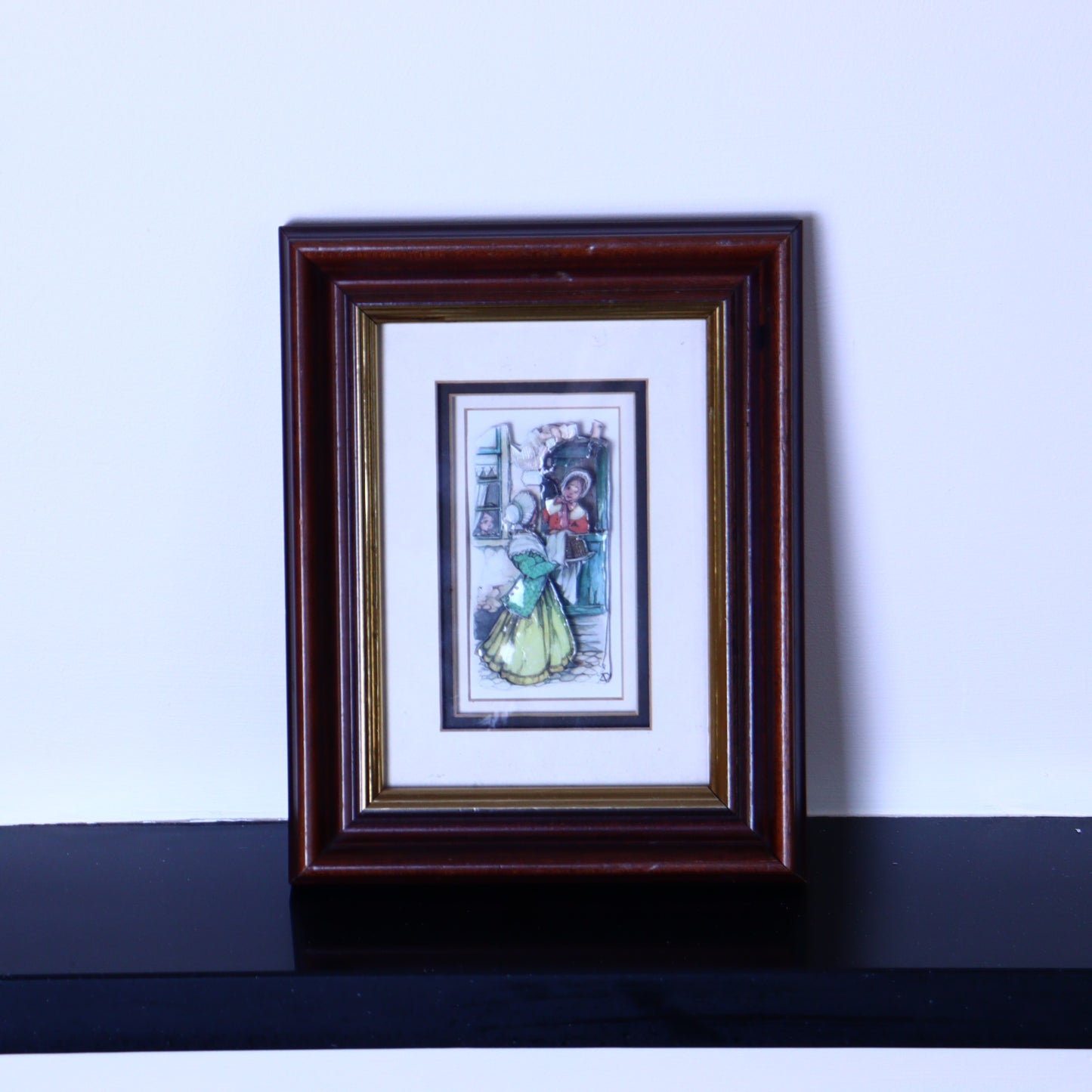 A framed 3D illustration of two women talking, created by the Dutch artist Anton Pieck, with a brown wooden frame and a white background.