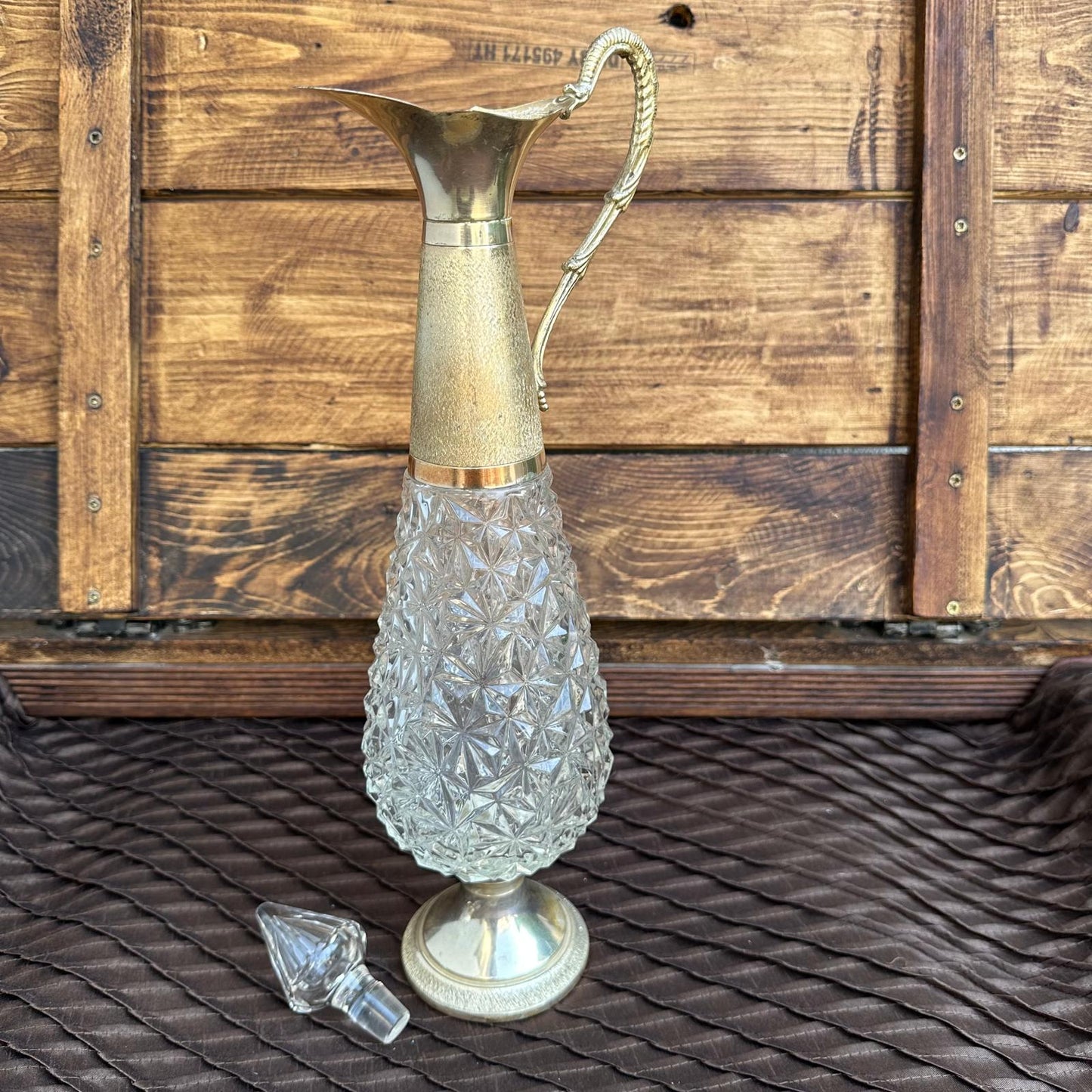 Decorative glass pitcher with a gold handle on a wooden surface