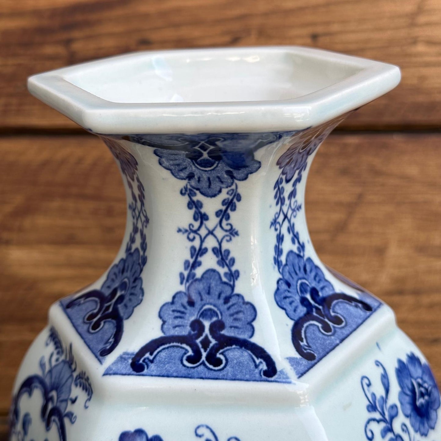 Hexagonal ceramic vase with blue floral patterns on a wooden surface
