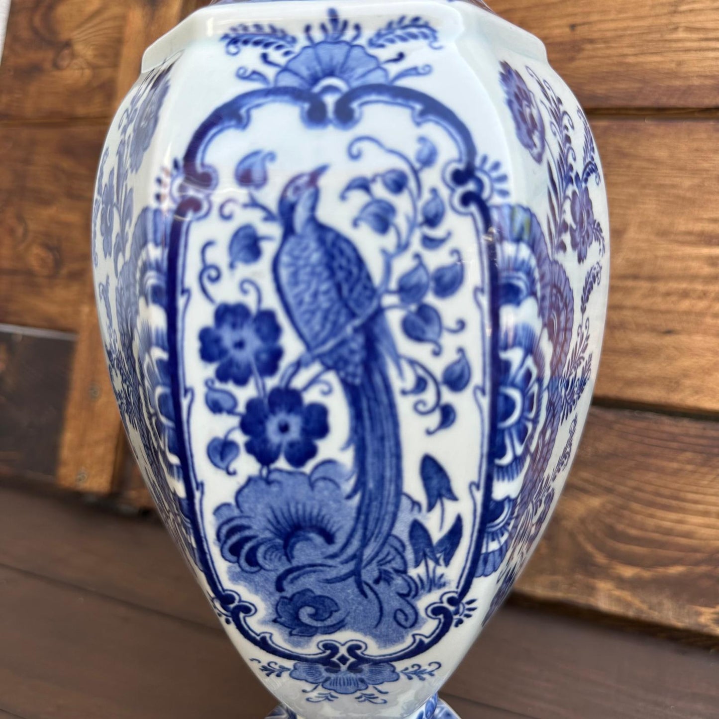 Blue and white ceramic vase with intricate floral and bird design on a wooden surface