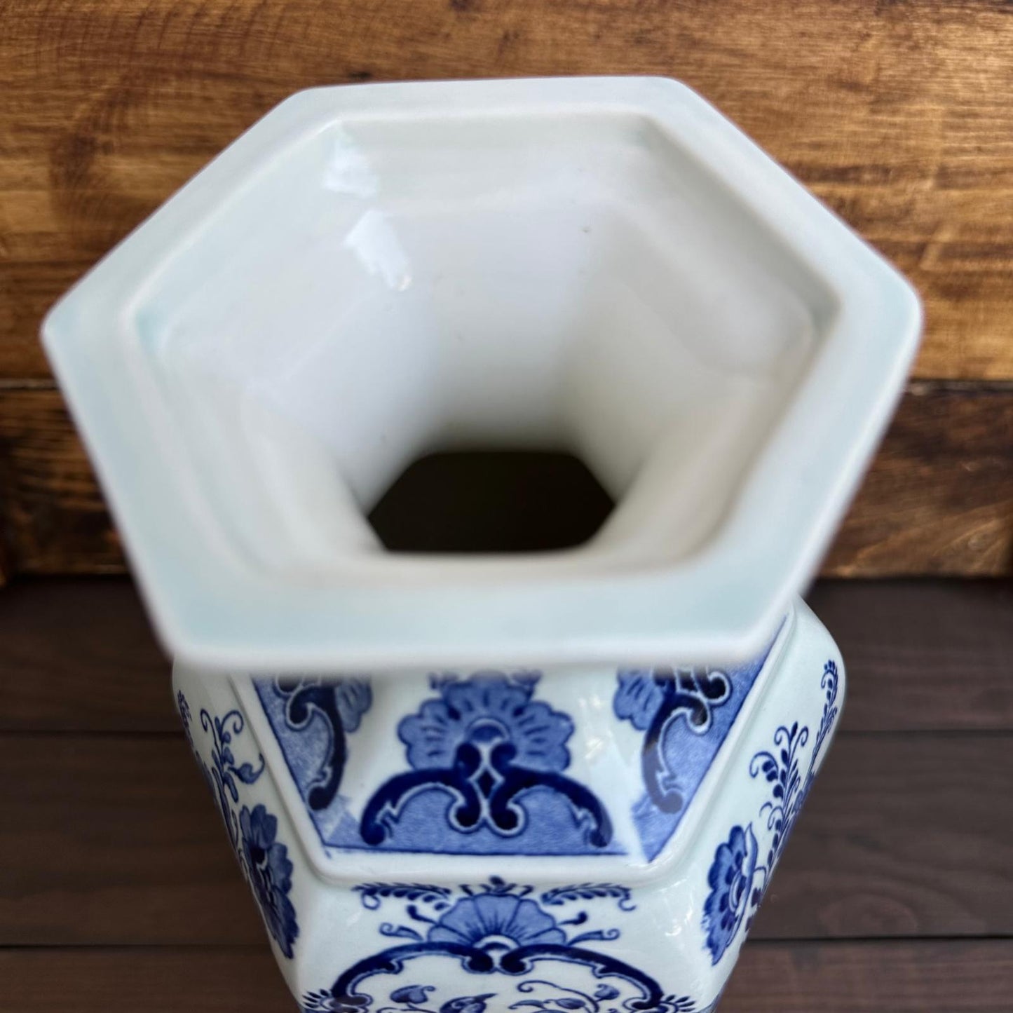 Hexagonal ceramic vase with blue and white patterns on a wooden surface