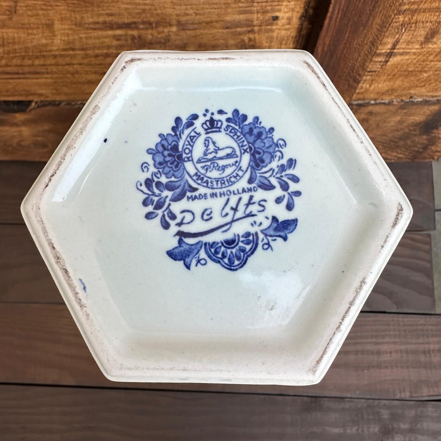 Hexagonal ceramic plate with blue floral design and text on a wooden surface