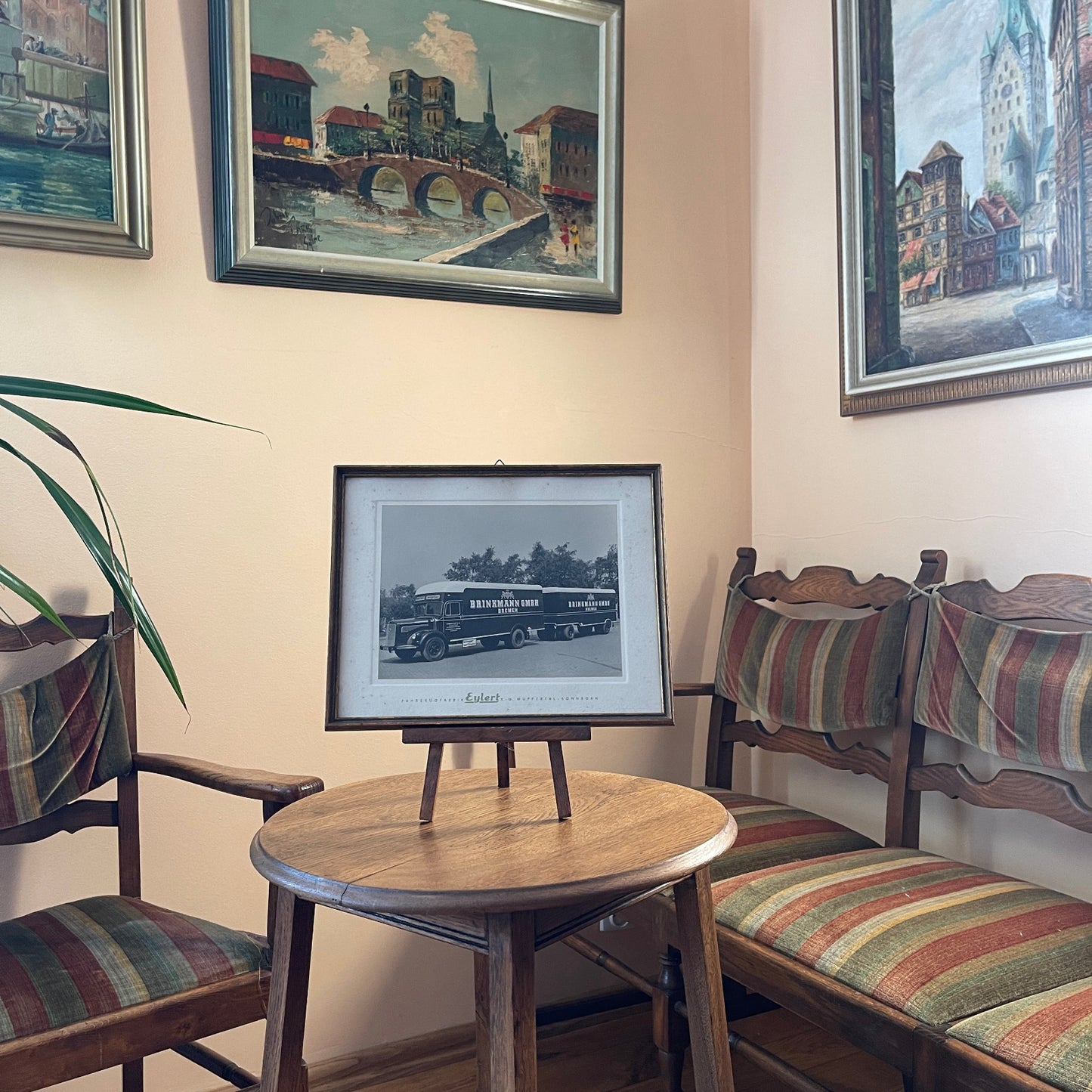 Room interior with wooden furniture, striped cushioned chairs, and framed pictures on the wall.