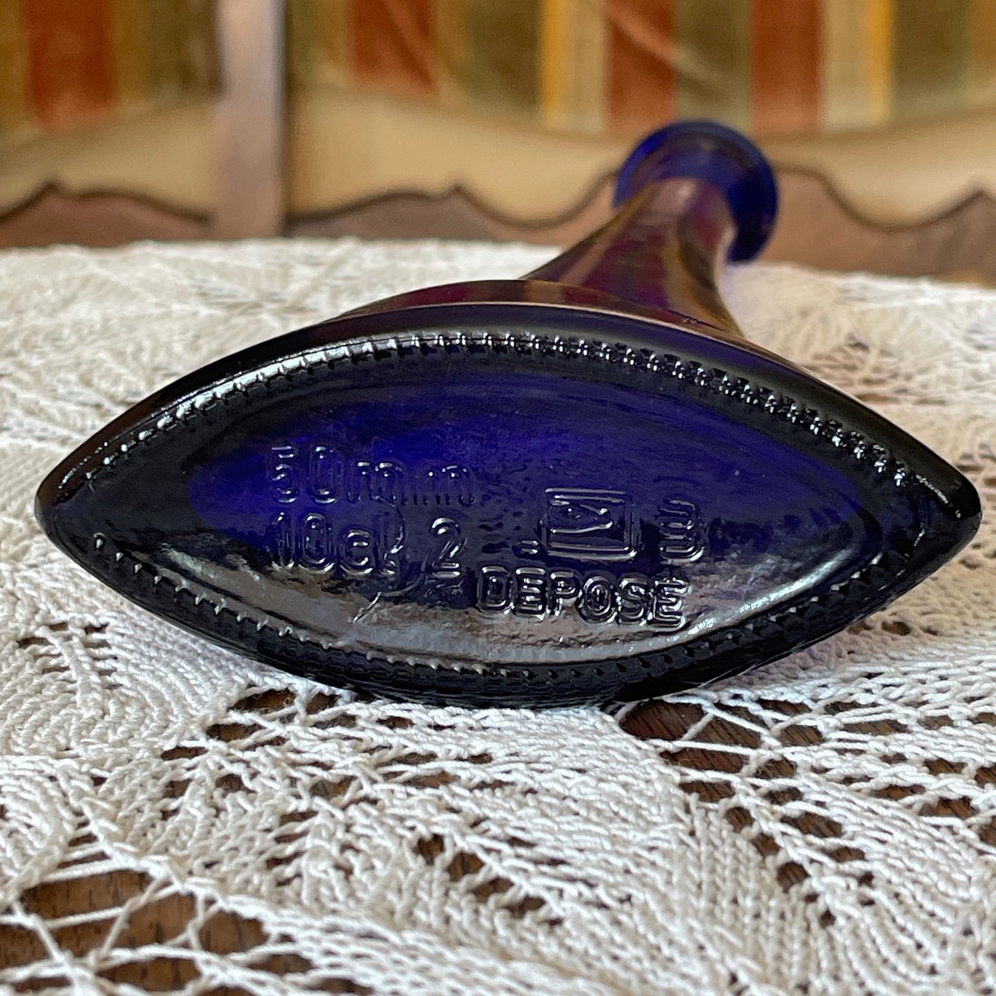Blue glass bottle cap on a lace tablecloth with a blurred background
