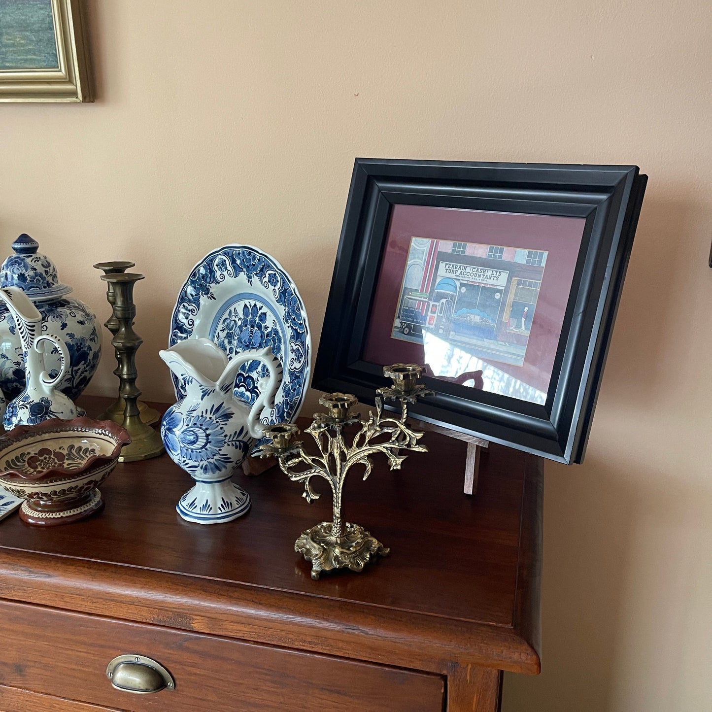 Decorative items including a framed picture, blue and white ceramic pitcher, and other ornaments on a wooden surface.