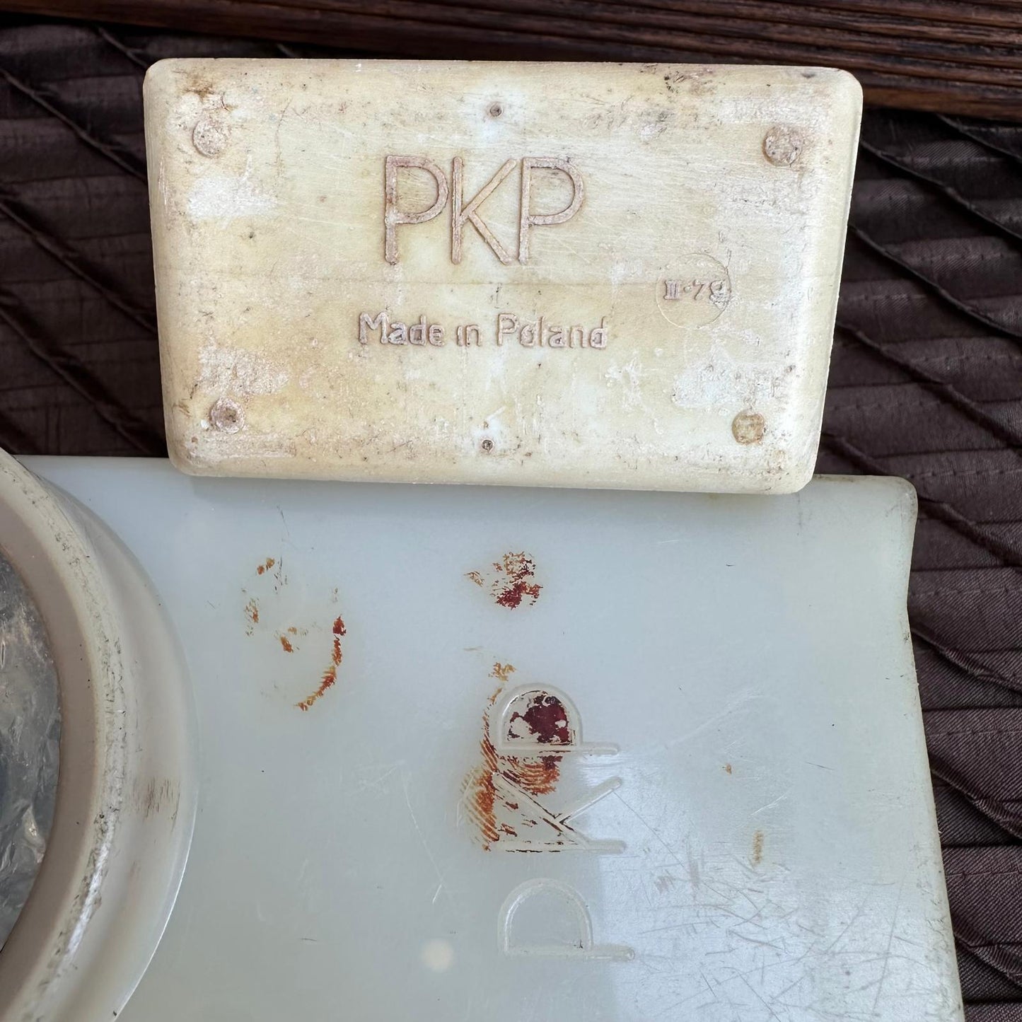 Bar of soap with 'PKP' branding on a dish with similar branding, on a textured surface.