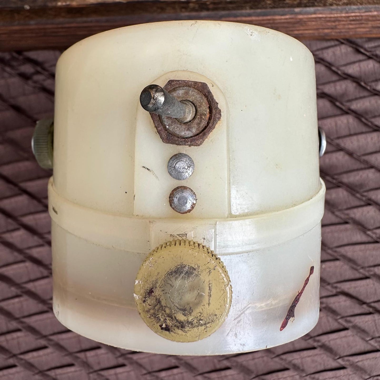 Vintage mechanical component with gears and screws on a textured surface