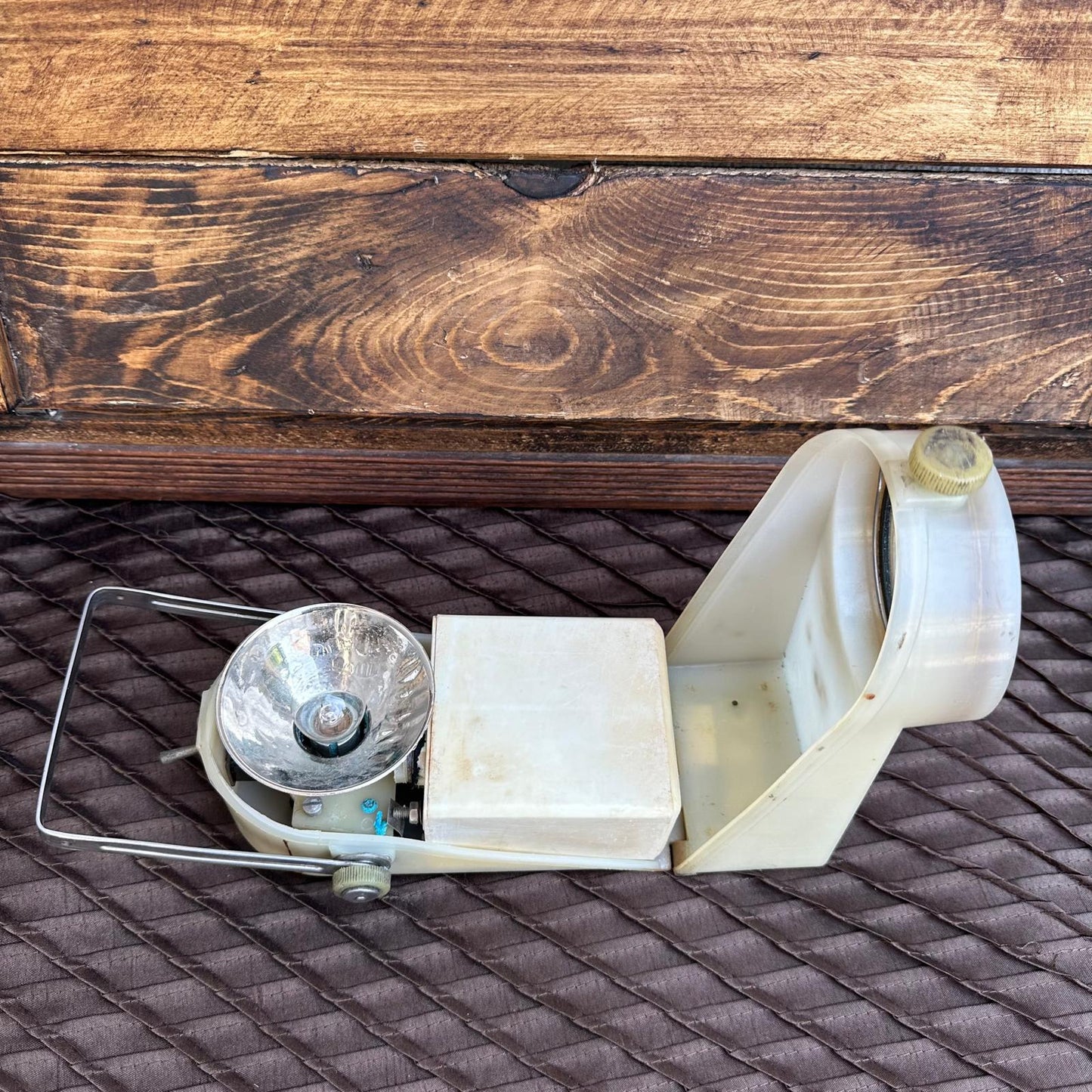 Vintage camping stove on a textured surface with wooden background