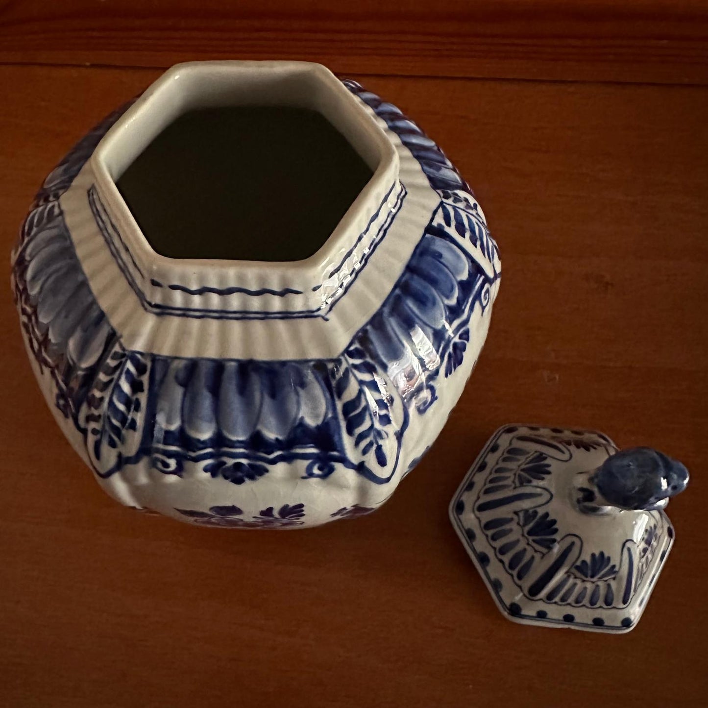 Hexagonal ceramic jar with blue and white floral patterns on a wooden surface