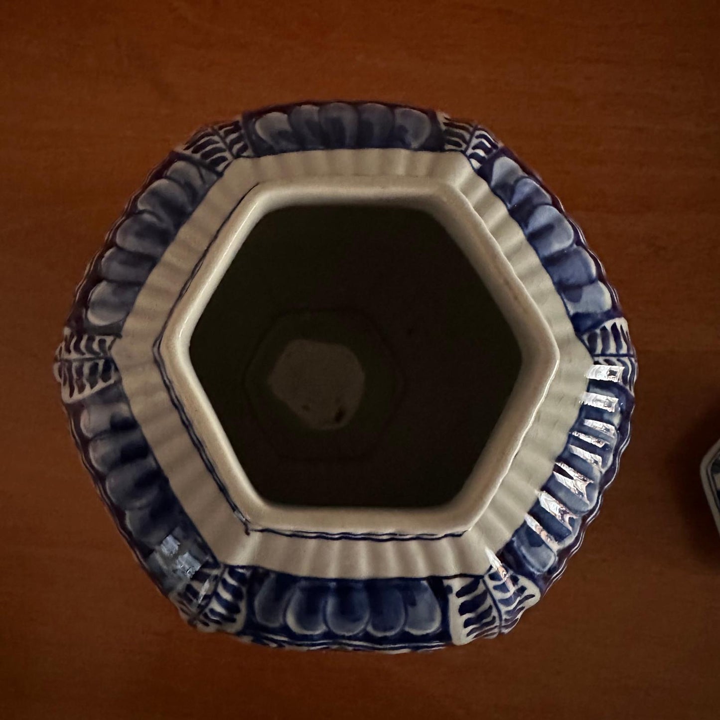 Hexagonal ceramic vase with blue and white patterns on a brown background