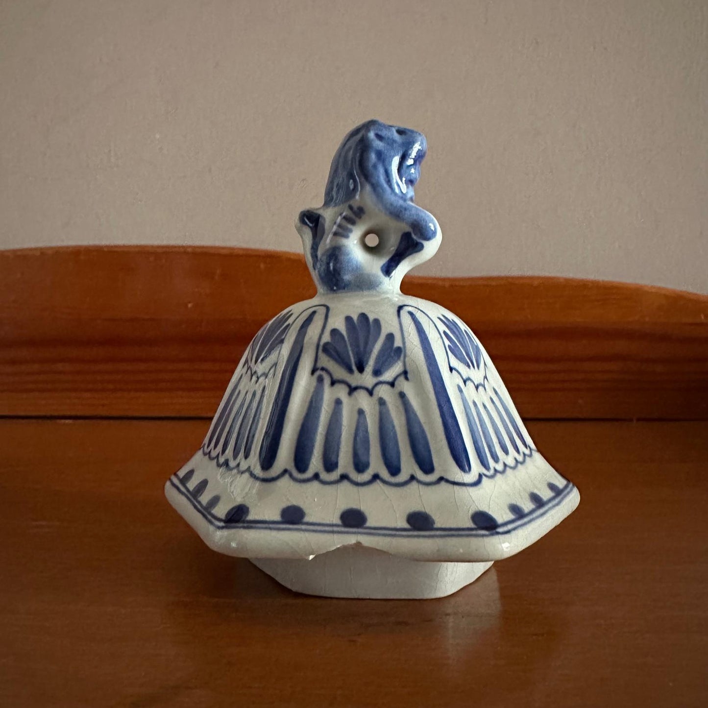 Ceramic bell with blue and white design on a wooden surface