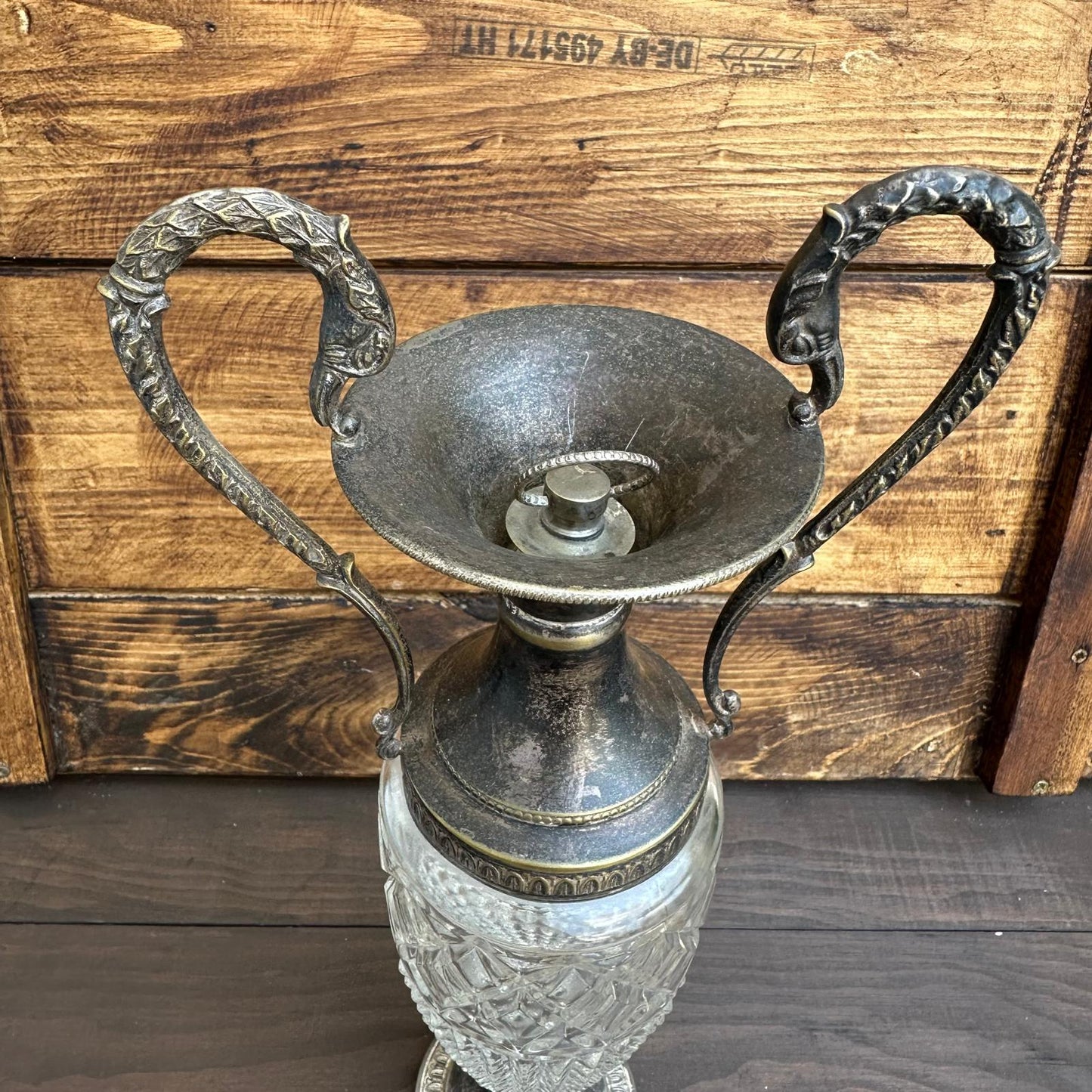 Decorative lamp with crystal base and metal shade against a wooden background