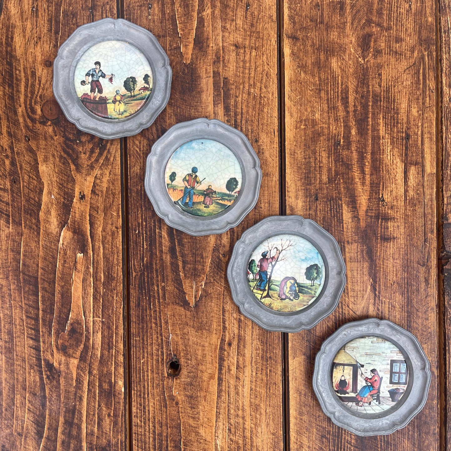 Set of four decorative plates with scenic illustrations on a wooden surface