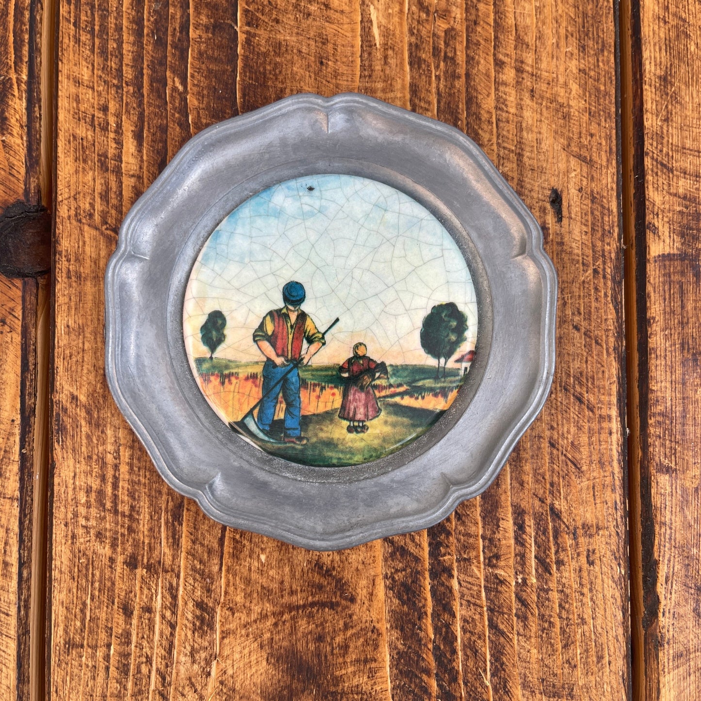 Decorative plate with a scenic painting of two people on a wooden surface