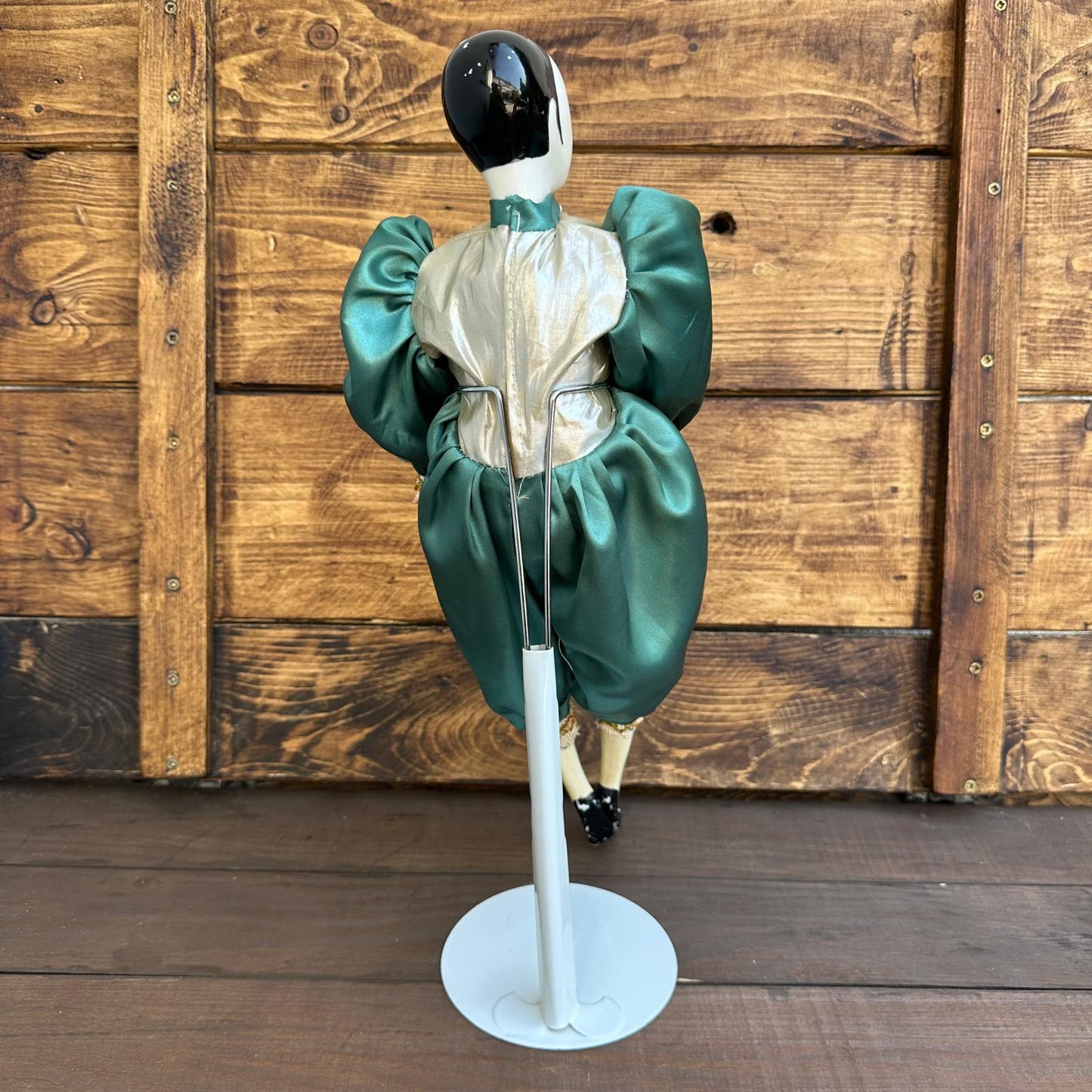 Mannequin wearing a green dress with a white base against a wooden background