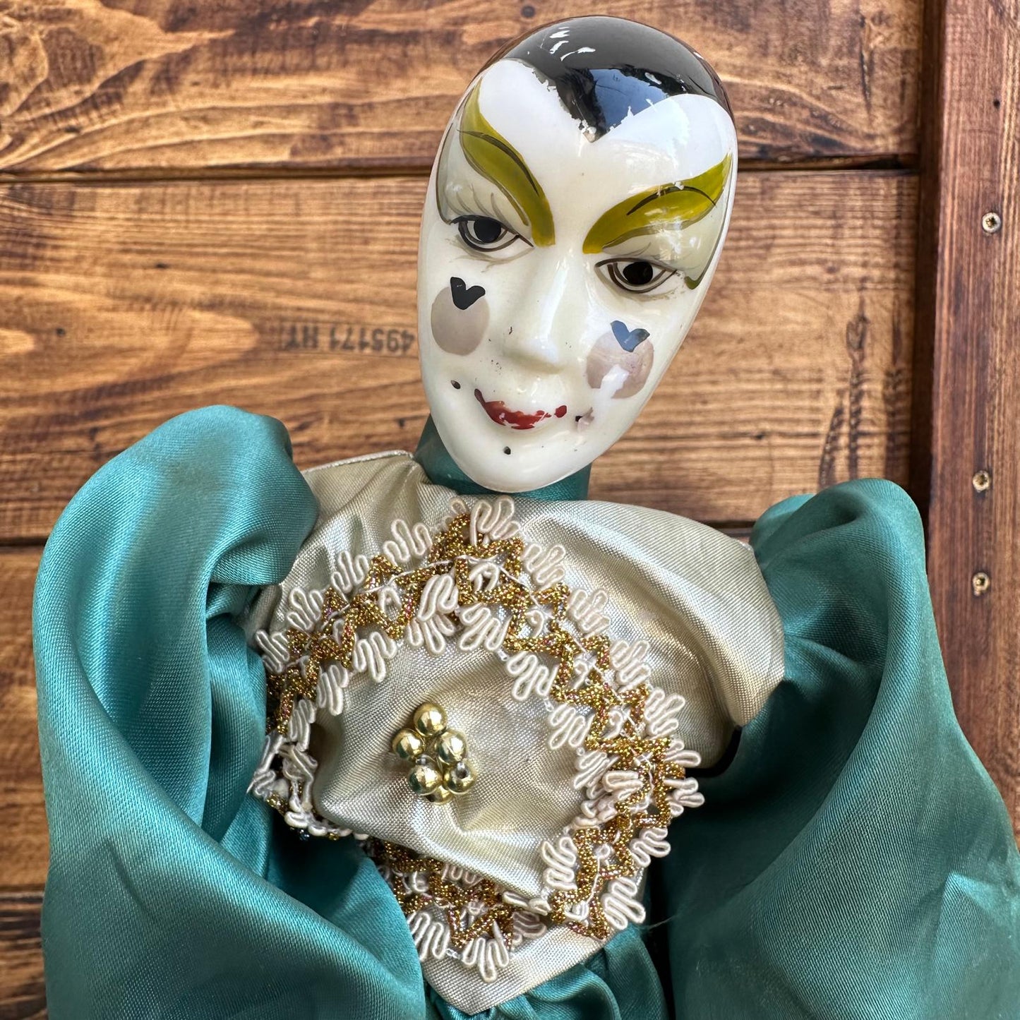 Ceramic mask with decorative clothing on a wooden background