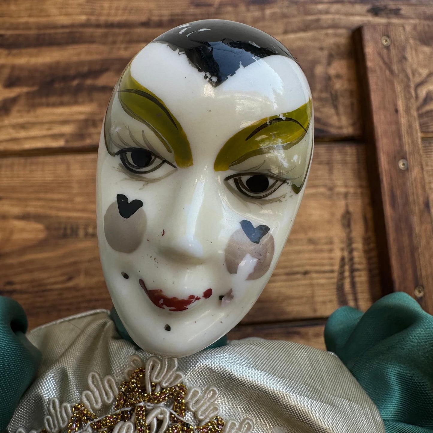 Decorative mask with painted features on a wooden surface