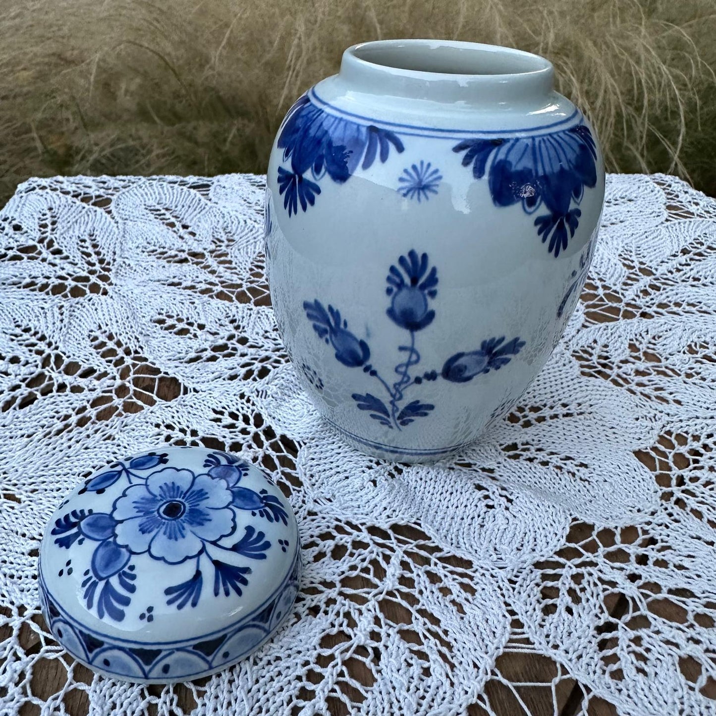 Blue and white ceramic jar with matching lid on a lace tablecloth