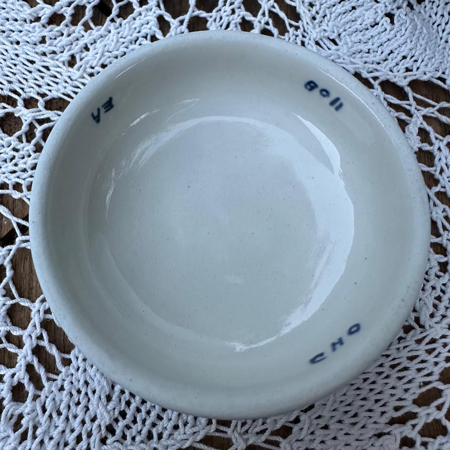 White ceramic bowl with visible branding on a lace doily
