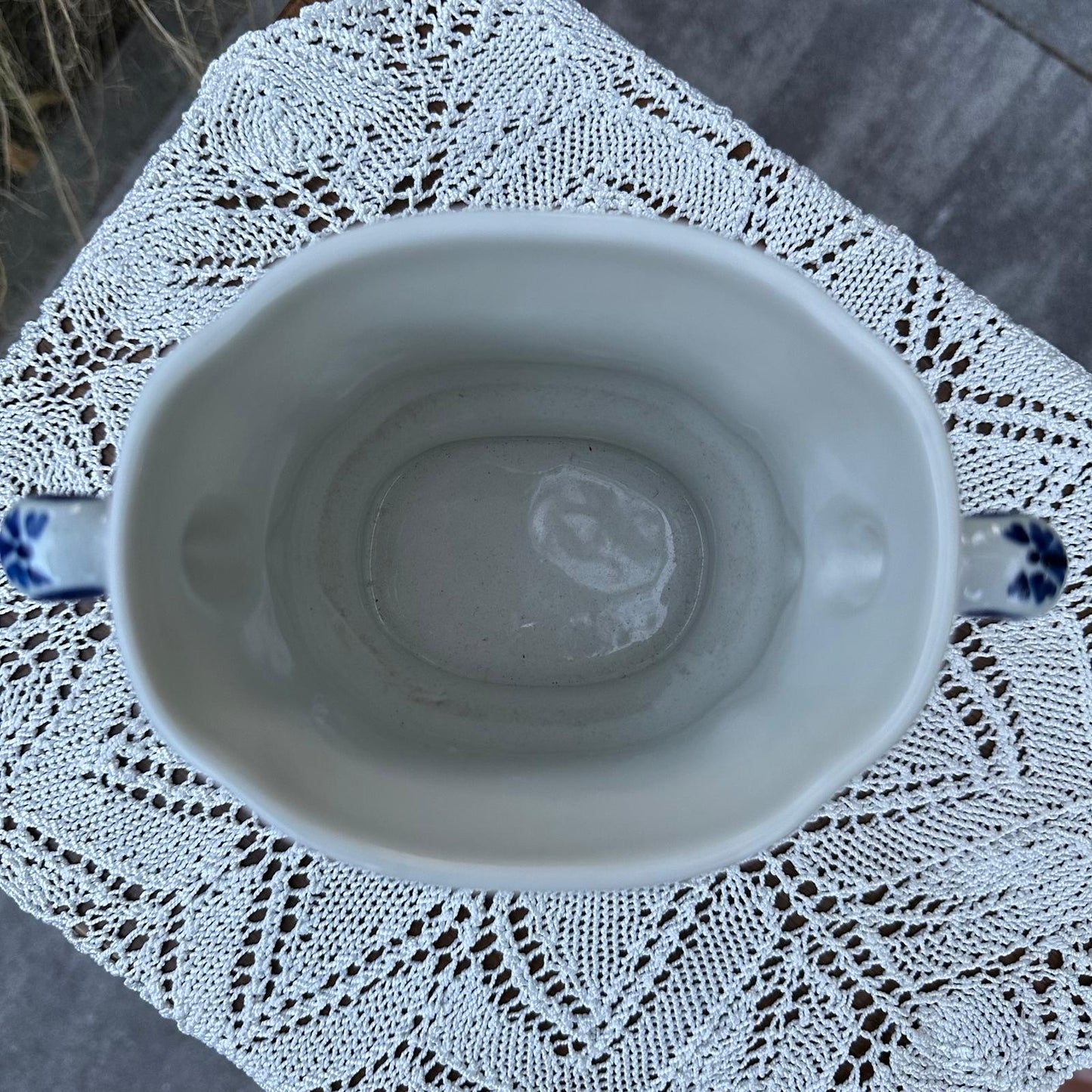 White ceramic cup with blue accents on a lace doily