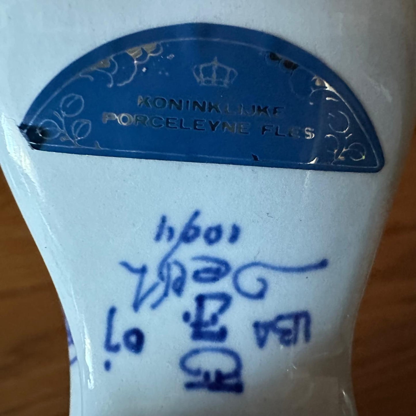 Close-up of a white ceramic item with blue text and 'Koninklijke Porceleyne Fles' branding.