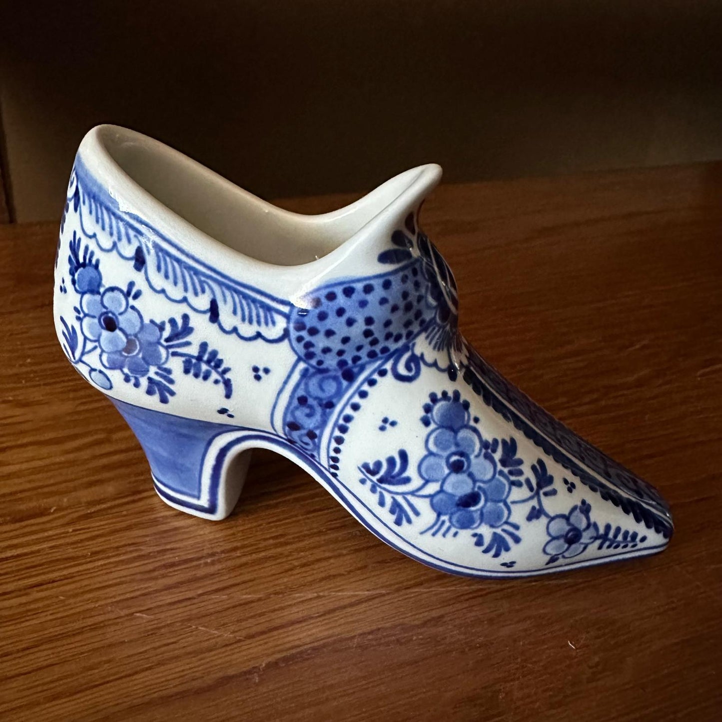 Ceramic shoe with blue floral patterns on a wooden surface