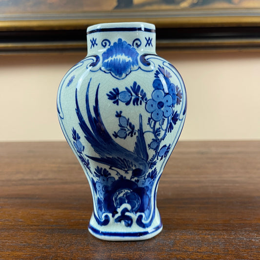 Blue and white ceramic Royal Delft vase with floral patterns on a wooden surface.